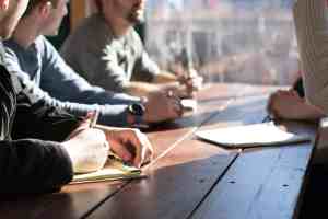 Real estate temp agency vs permanent recruitment discussion between a property professional and recruitment consultant in a modern office